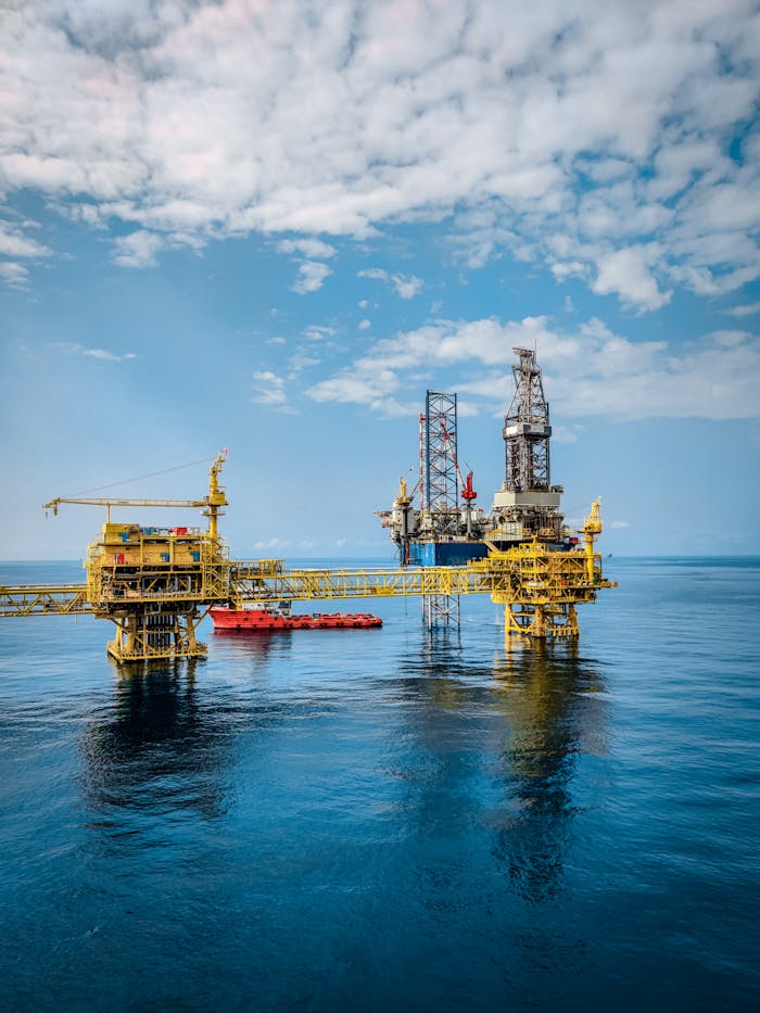 A vibrant offshore oil rig under a clear sky, reflecting in the calm blue sea.